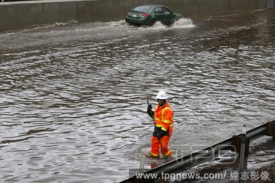 美國洛杉磯，豪雨過後，工人走在淹水的5號公路上。 